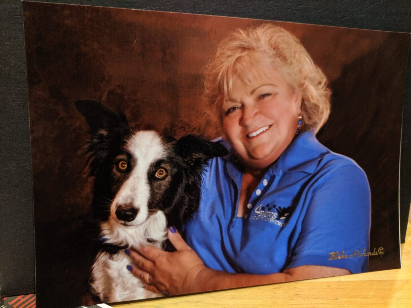 A woman holding her dog in front of a wall.